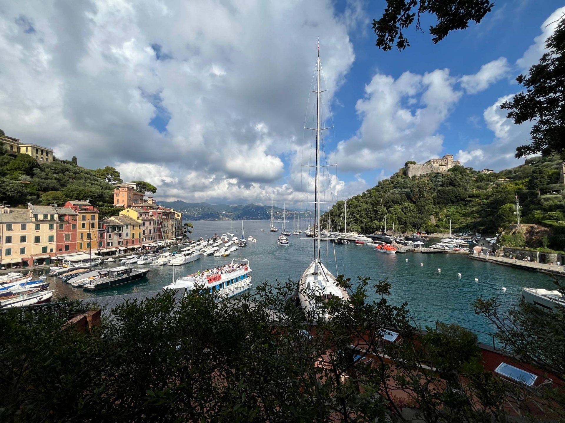 Vista do porto de Portofino, com barcos ancorados, casas coloridas e o castelo na colina