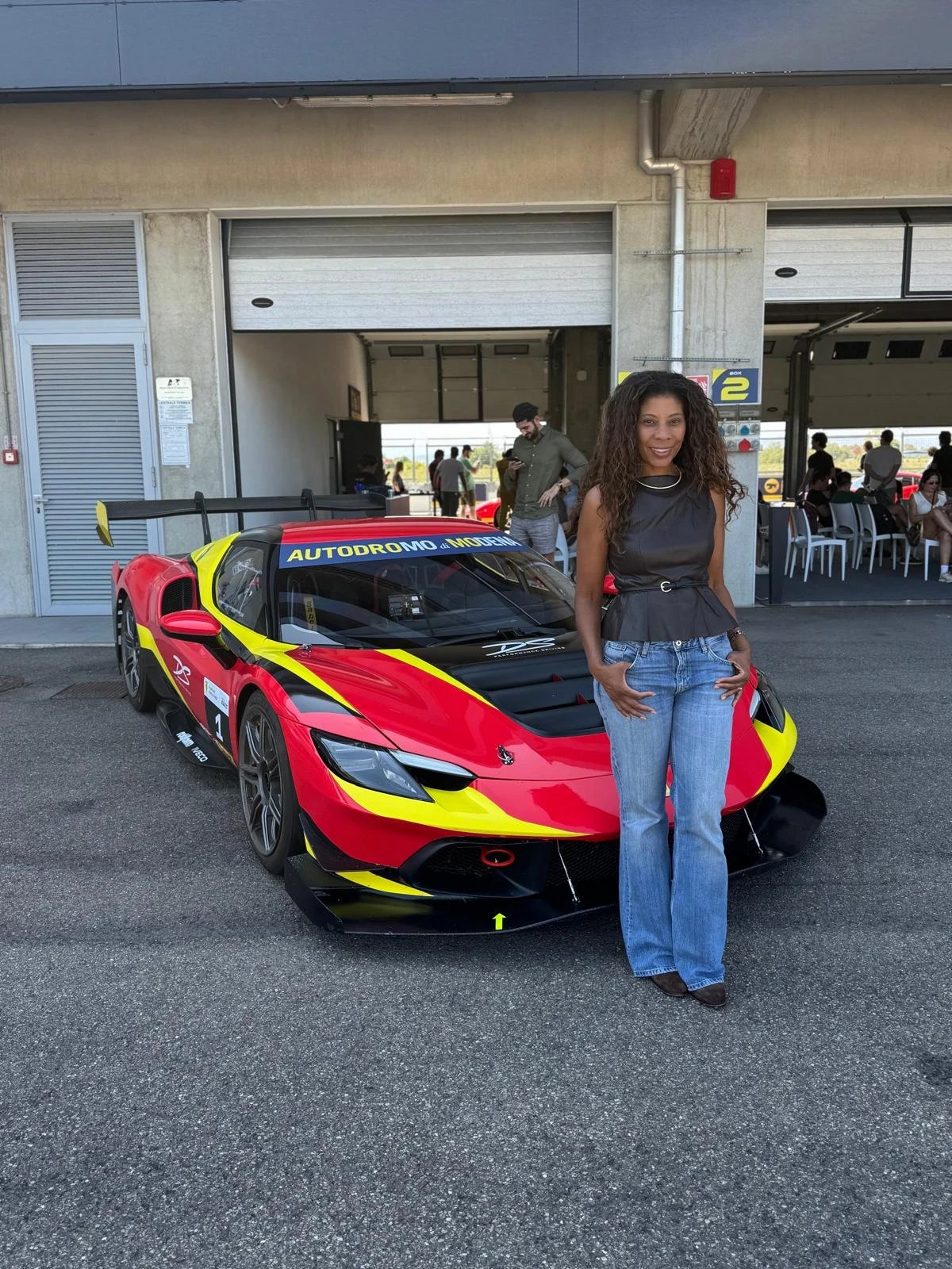 Denise Brito ao lado de um carro de corrida no Autodromo di Modena