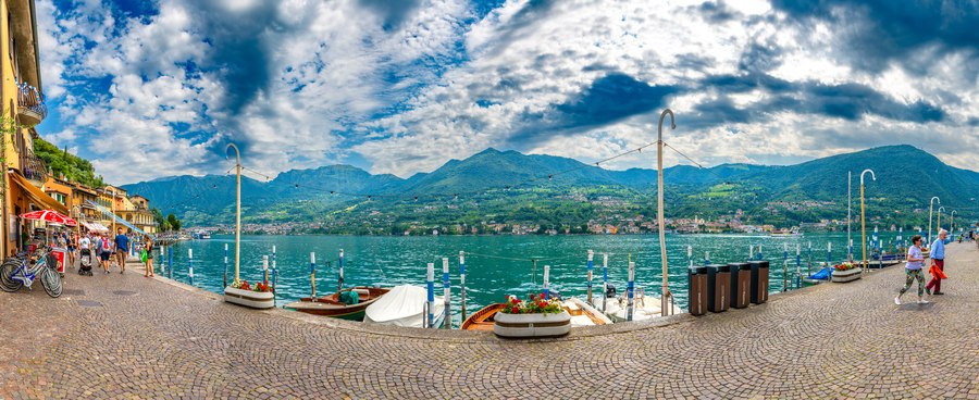 Orla do Lago d'Iseo com barcos, montanhas ao fundo e céu dramático