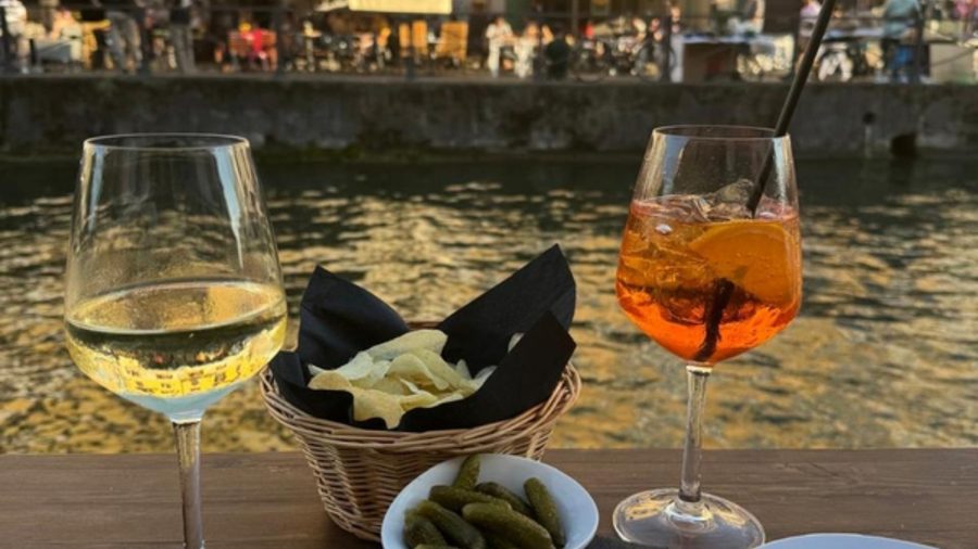 Aperitivo à beira de um canal em Milão, com taças de vinho branco e spritz e uma cesta de petiscos
