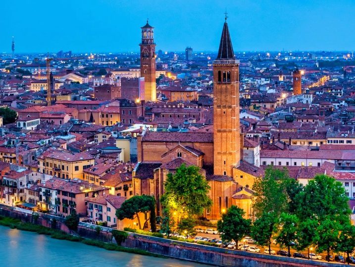 Vista aérea de Verona ao entardecer, com a Torre dos Lamberti, o campanário de Santa Anastasia e o Rio Adige